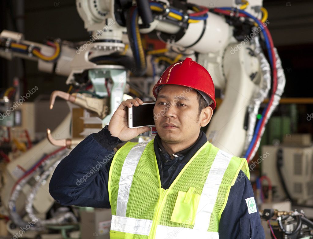 Operator monitoring a robotized machining cell on the shop floor